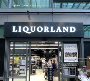 Liquorland North Sydney illuminated main store sign above the entrance with bottle shop interior visible.